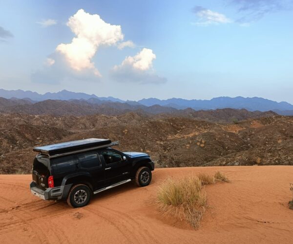 A black jeep is parked on a sand dune.