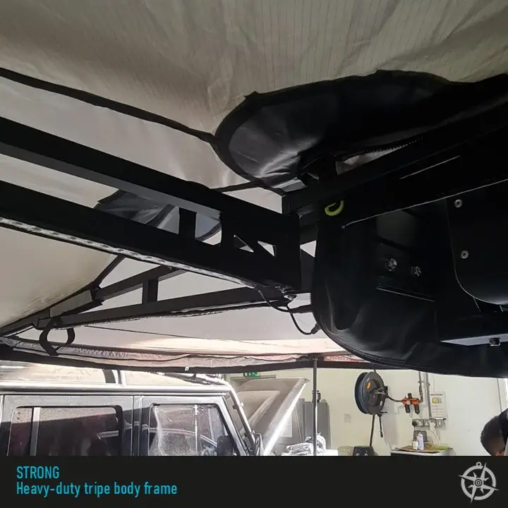 Slide3-3.jpg Inside the vehicle, you see the heavy-duty black metal frame labeled tripe body frame, designed for overlanding. The setup includes a 270 Double Hinge Awning 2.0m, with tools on the wall and another vehicle visible in the background, enhancing its rugged appeal.