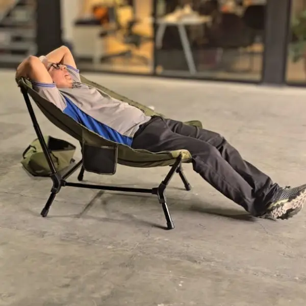 chicari chillax chair (5) A person in a gray and blue shirt with black pants relaxes indoors on the Chicari Chillax Chair, hands behind their head and legs stretched out comfortably.